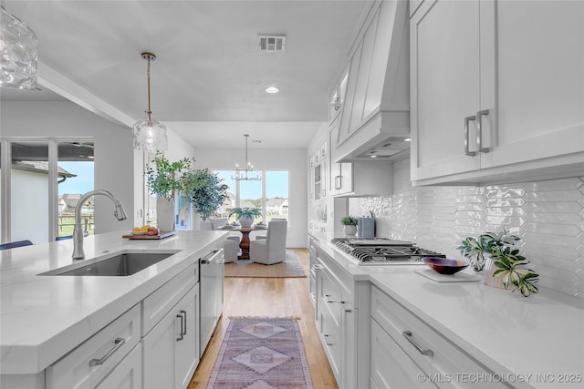 kitchen featuring premium range hood, sink, white cabinets, light hardwood / wood-style floors, and stainless steel appliances