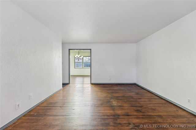 spare room featuring a notable chandelier and dark hardwood / wood-style flooring