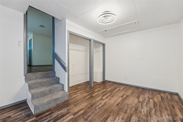 unfurnished bedroom with dark wood-type flooring, a textured ceiling, and a closet