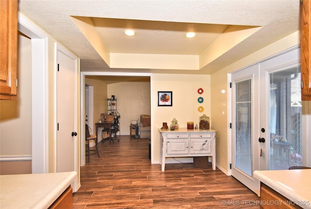 hall with french doors, a tray ceiling, and dark wood-type flooring