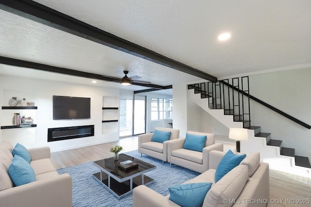7850 S Park Ave, Broken Arrow, OK 74011 - living area with wood finished floors, beam ceiling, stairway, a glass covered fireplace, and ceiling fan