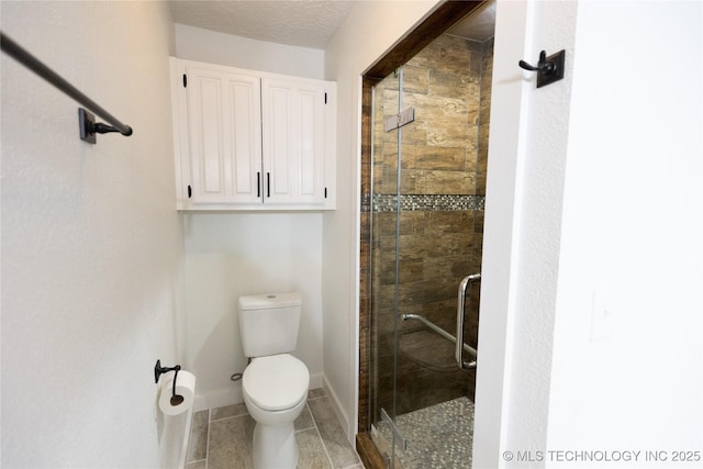 bathroom featuring an enclosed shower, a textured ceiling, and toilet