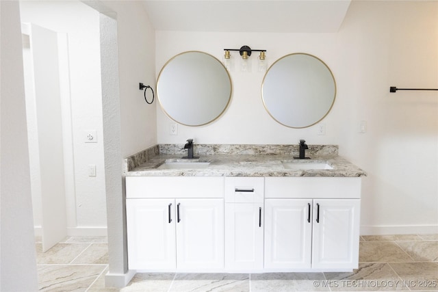 bathroom featuring double vanity, a sink, and baseboards