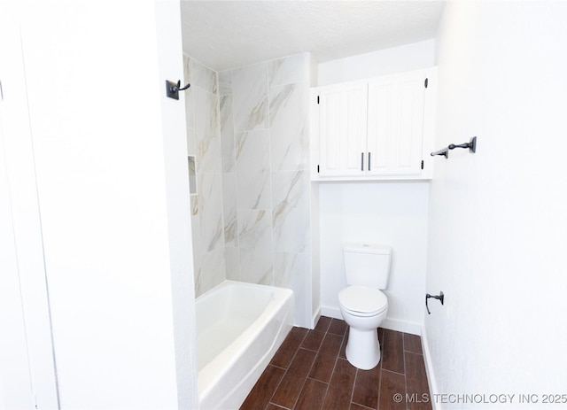 bathroom featuring tiled shower / bath, a textured ceiling, and toilet