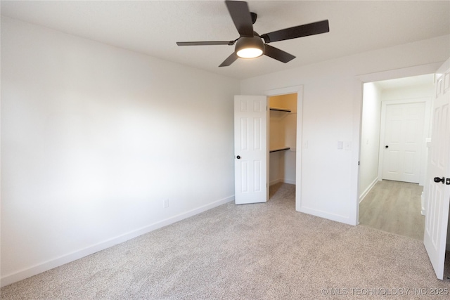 unfurnished bedroom featuring baseboards, a ceiling fan, a spacious closet, carpet flooring, and a closet