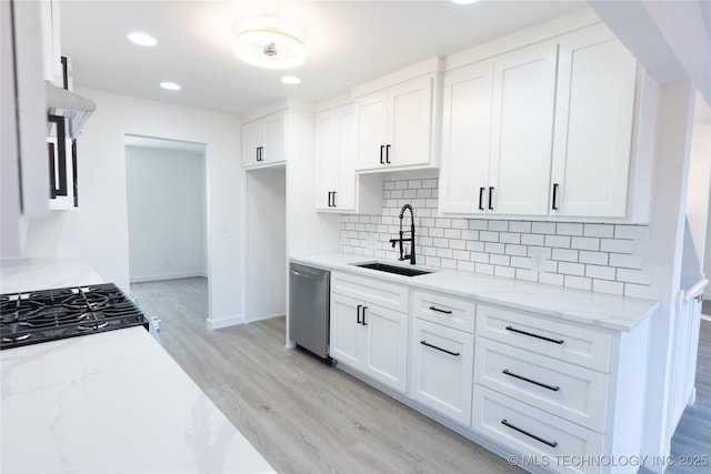 kitchen with light wood finished floors, white cabinets, a sink, light stone countertops, and dishwasher