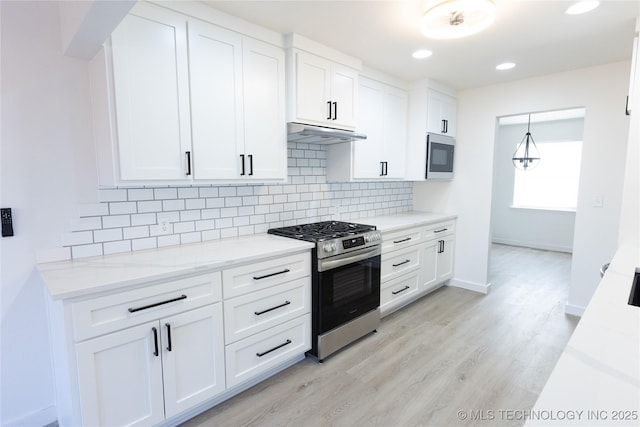 kitchen with under cabinet range hood, tasteful backsplash, appliances with stainless steel finishes, and white cabinets