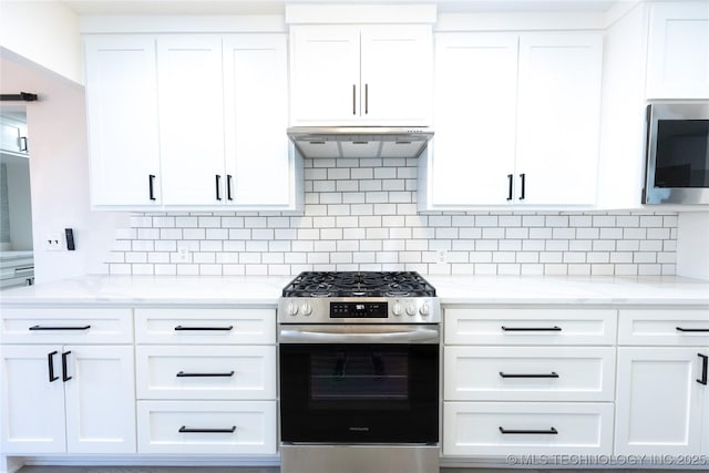 7850 S Park Ave, Broken Arrow, OK 74011 - kitchen featuring appliances with stainless steel finishes, under cabinet range hood, white cabinets, decorative backsplash, and light stone counters