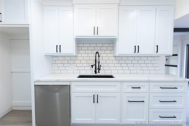 kitchen featuring sink, white cabinetry, dishwasher, light stone countertops, and backsplash