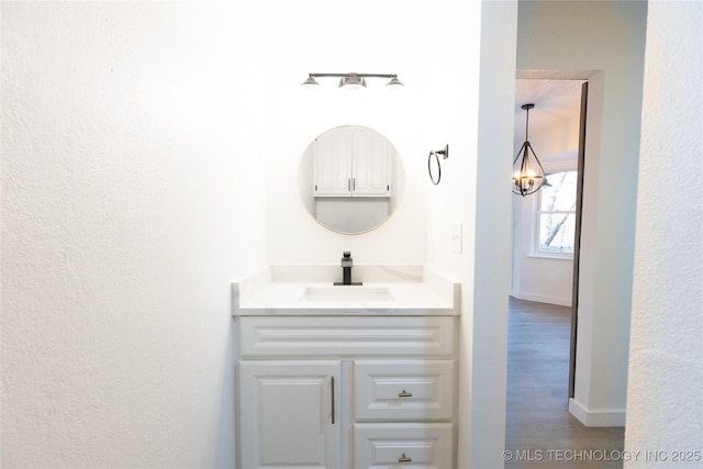 bathroom with vanity, wood-type flooring, and an inviting chandelier