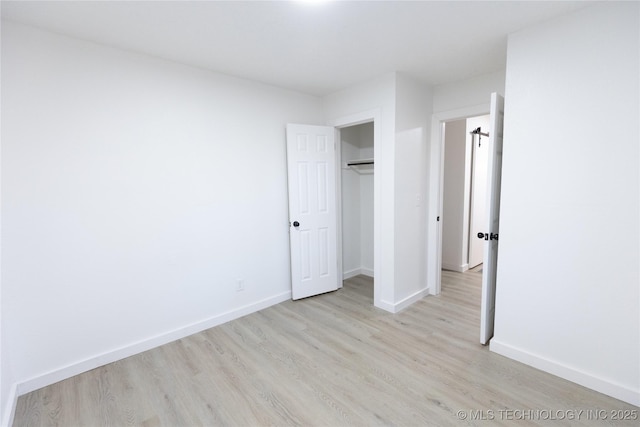 unfurnished bedroom with light wood finished floors, baseboards, and a closet