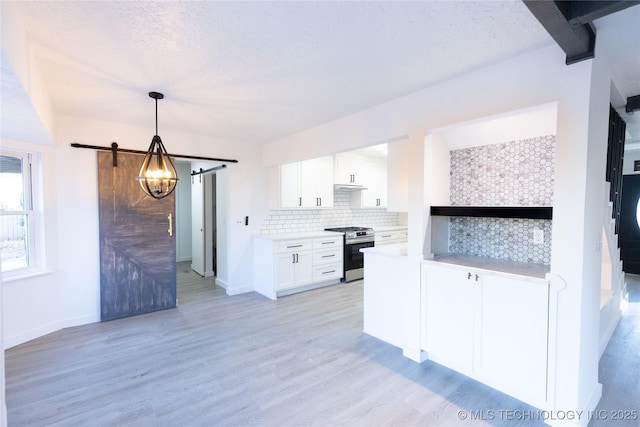 kitchen with tasteful backsplash, light countertops, a barn door, gas stove, and white cabinets