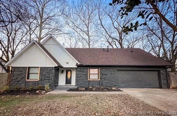 view of front of home with a garage, stone siding, fence, and concrete driveway