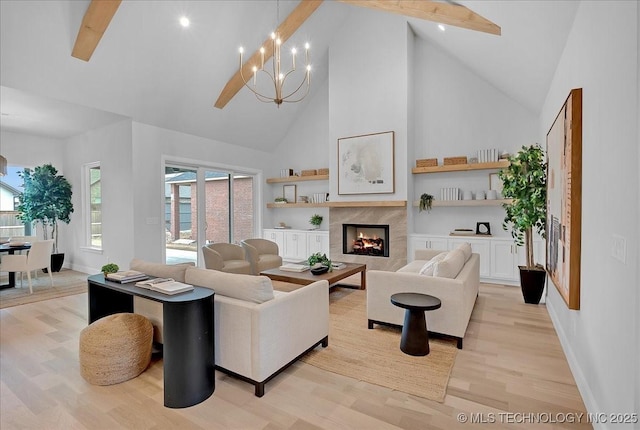 living room with an inviting chandelier, high vaulted ceiling, beamed ceiling, a tiled fireplace, and light wood-type flooring