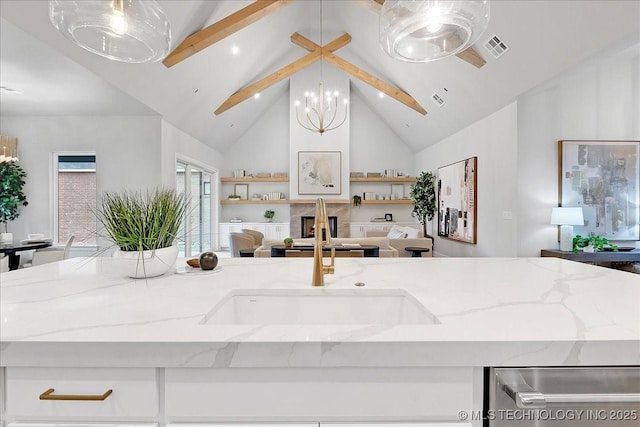 kitchen with light stone countertops, stainless steel dishwasher, pendant lighting, and sink