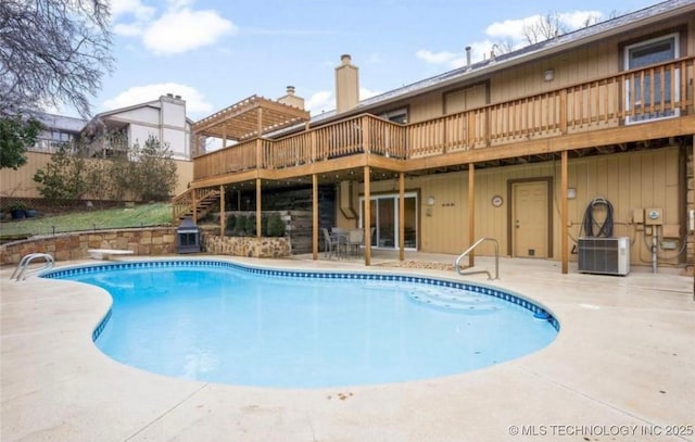 view of swimming pool with a wooden deck, a diving board, and a patio area