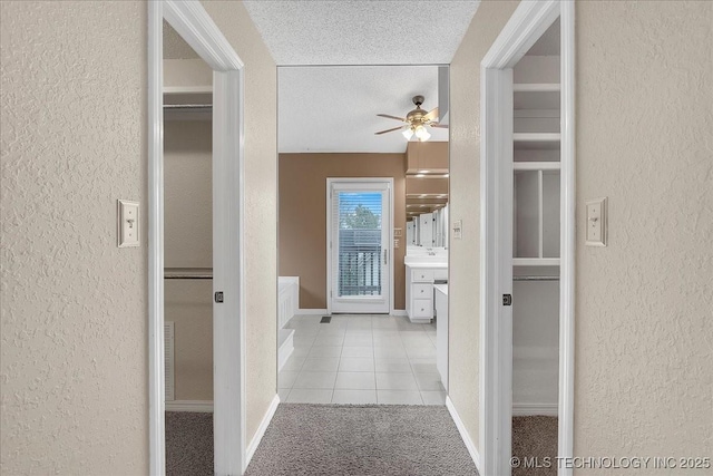 hallway featuring light tile patterned flooring, sink, and a textured ceiling