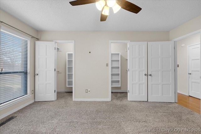 unfurnished bedroom featuring ceiling fan, carpet floors, a textured ceiling, a spacious closet, and a closet