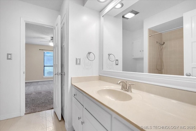 bathroom featuring ceiling fan, tiled shower, vanity, and a textured ceiling