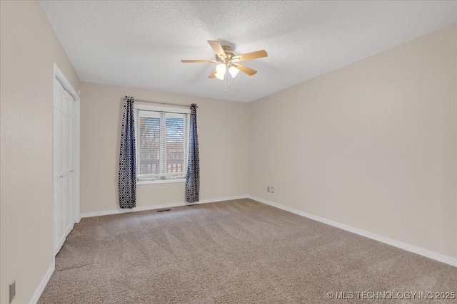 carpeted empty room with ceiling fan and a textured ceiling