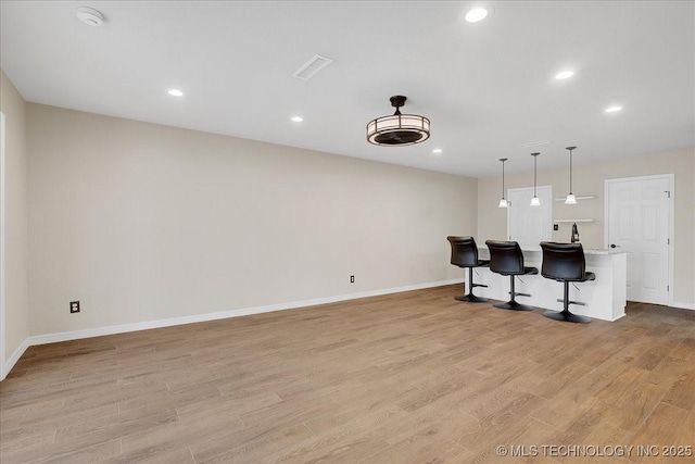 kitchen featuring a center island, light hardwood / wood-style flooring, a breakfast bar, and decorative light fixtures