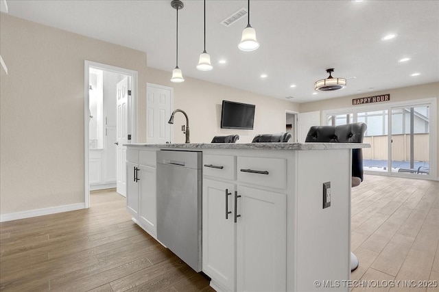 kitchen featuring a kitchen island with sink, hanging light fixtures, white cabinets, stainless steel dishwasher, and light wood-type flooring