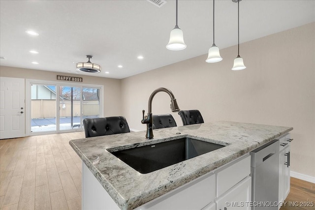 kitchen with sink, white cabinetry, light stone counters, dishwasher, and a kitchen island