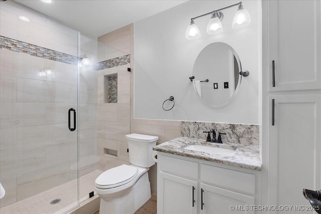 bathroom featuring vanity, a shower with door, toilet, and tile walls