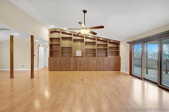 unfurnished living room with built in shelves, vaulted ceiling, light wood-type flooring, ceiling fan, and a barn door