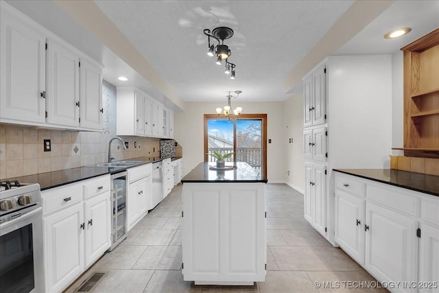 kitchen featuring sink, white cabinetry, stainless steel appliances, wine cooler, and a kitchen island