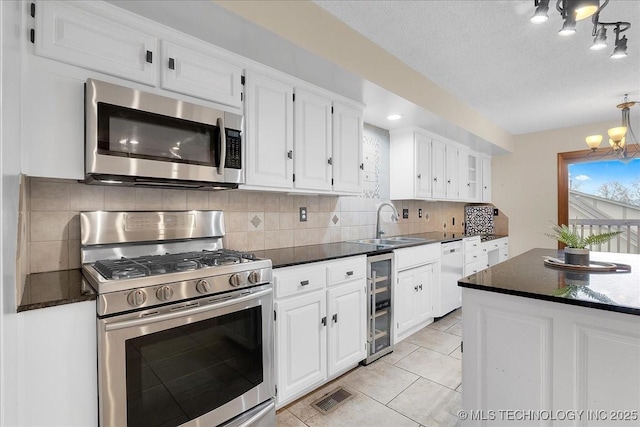 kitchen with sink, beverage cooler, white cabinets, and appliances with stainless steel finishes