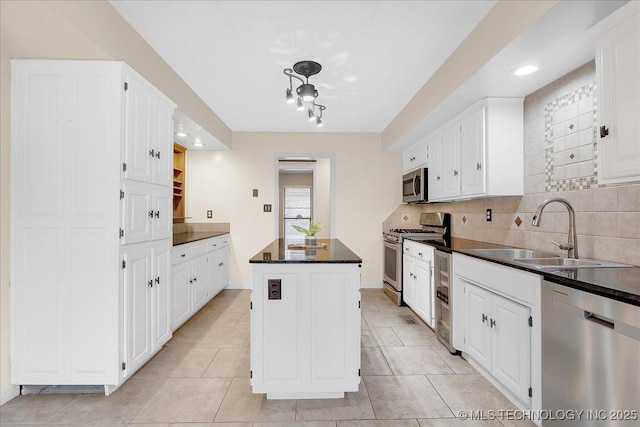 kitchen featuring appliances with stainless steel finishes, white cabinetry, sink, decorative backsplash, and a center island