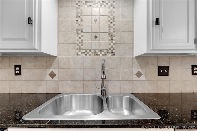 kitchen with white cabinetry, sink, and dark stone countertops