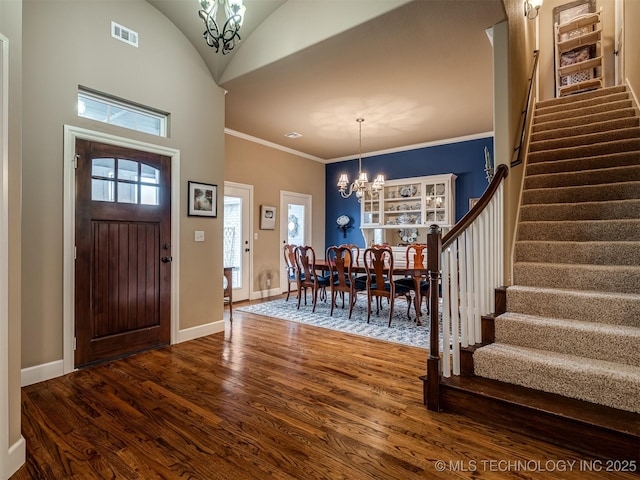 entrance foyer with crown molding, a notable chandelier, hardwood / wood-style flooring, and vaulted ceiling