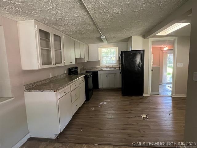 kitchen with dark wood-type flooring, black appliances, and white cabinets