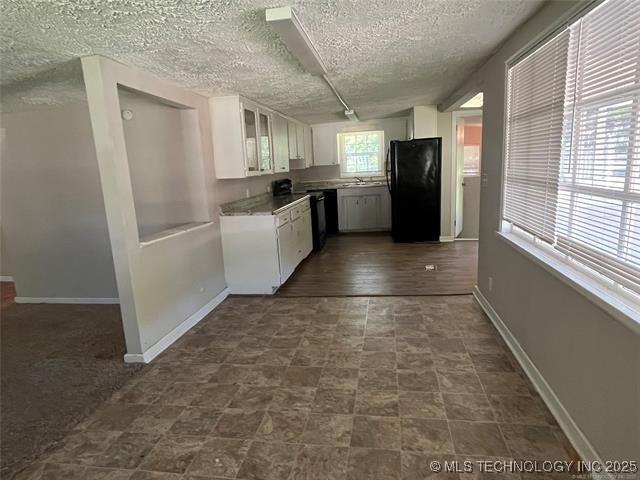 kitchen featuring black fridge, a textured ceiling, and white cabinets