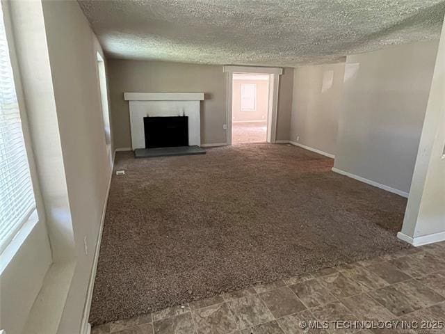 unfurnished living room featuring a textured ceiling and dark carpet