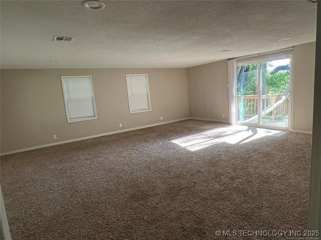 carpeted empty room featuring a textured ceiling