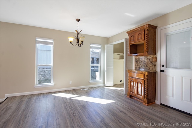 unfurnished dining area featuring dark hardwood / wood-style flooring and an inviting chandelier