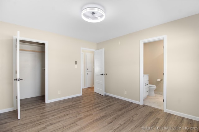 unfurnished bedroom featuring ensuite bath, a closet, and light wood-type flooring