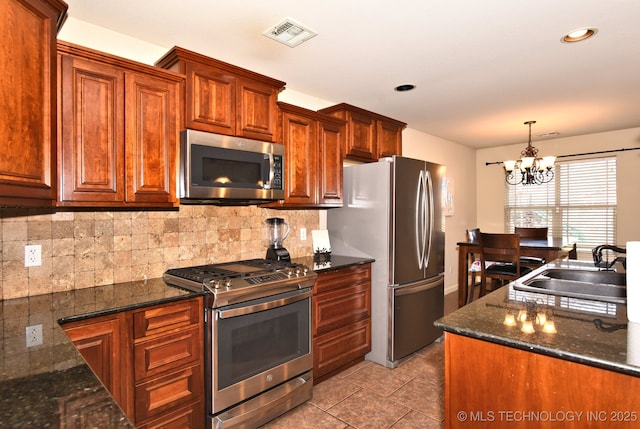 kitchen featuring dark stone countertops, stainless steel appliances, sink, and backsplash