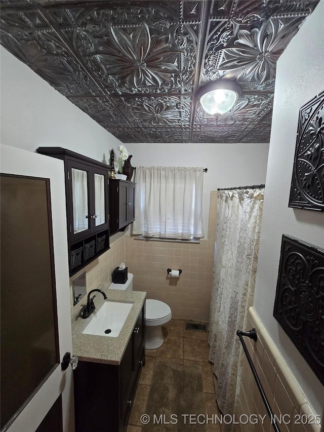 bathroom with vanity, tile walls, tile patterned floors, and toilet