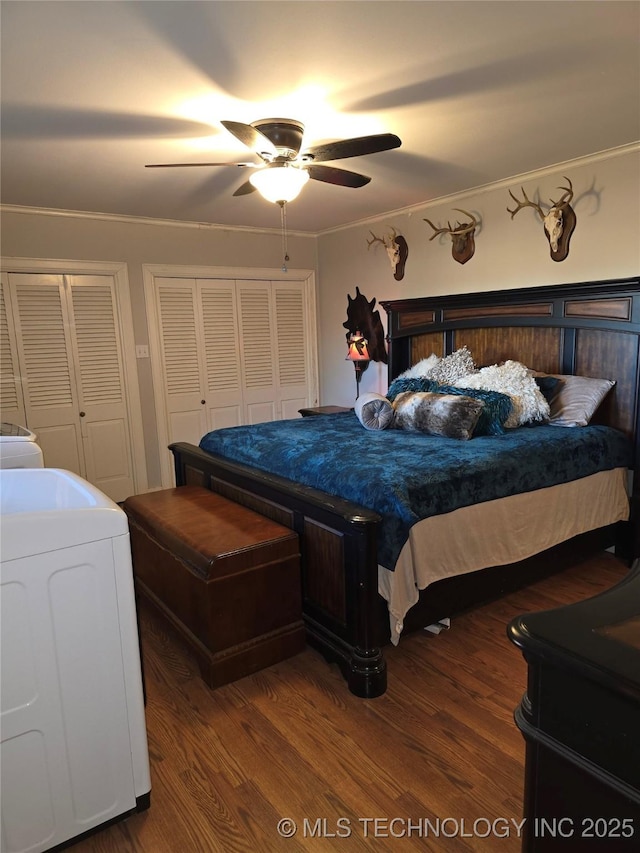 bedroom featuring ornamental molding, washer / dryer, hardwood / wood-style floors, and two closets