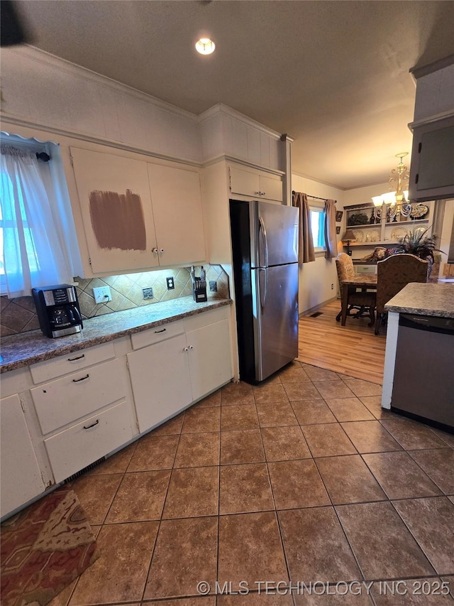 kitchen with pendant lighting, appliances with stainless steel finishes, tile patterned flooring, backsplash, and white cabinets