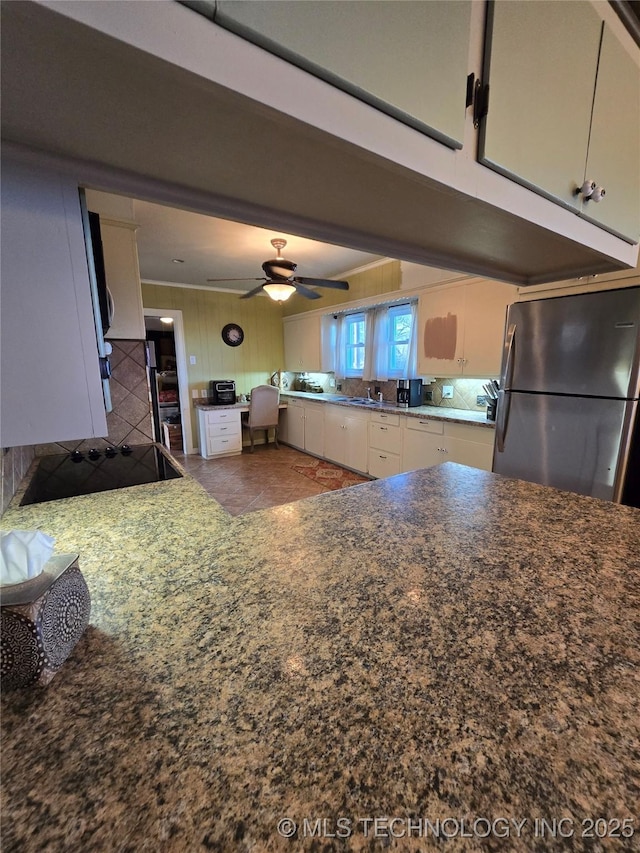 kitchen with sink, black electric cooktop, stainless steel fridge, ceiling fan, and white cabinets