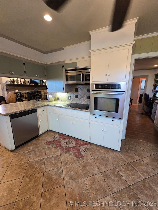 kitchen with tile patterned flooring, white cabinetry, appliances with stainless steel finishes, and ornamental molding