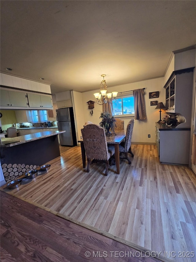 dining area with crown molding, a chandelier, and light wood-type flooring