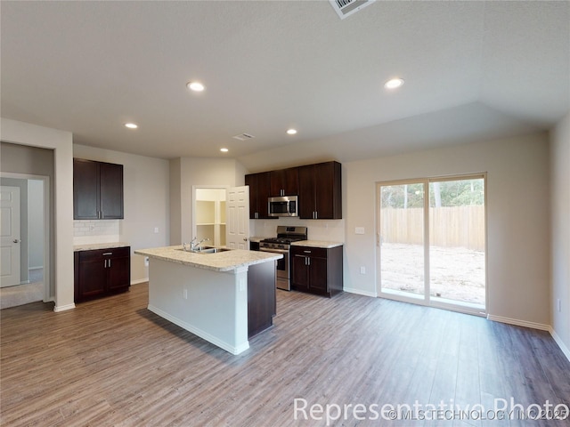 kitchen featuring dark brown cabinetry, sink, light hardwood / wood-style flooring, appliances with stainless steel finishes, and a kitchen island with sink