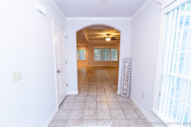 corridor with crown molding, a tray ceiling, and light tile patterned floors