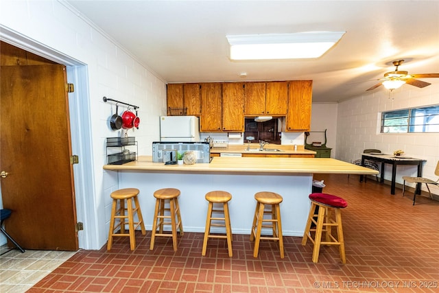 kitchen featuring sink, a breakfast bar area, ceiling fan, kitchen peninsula, and crown molding